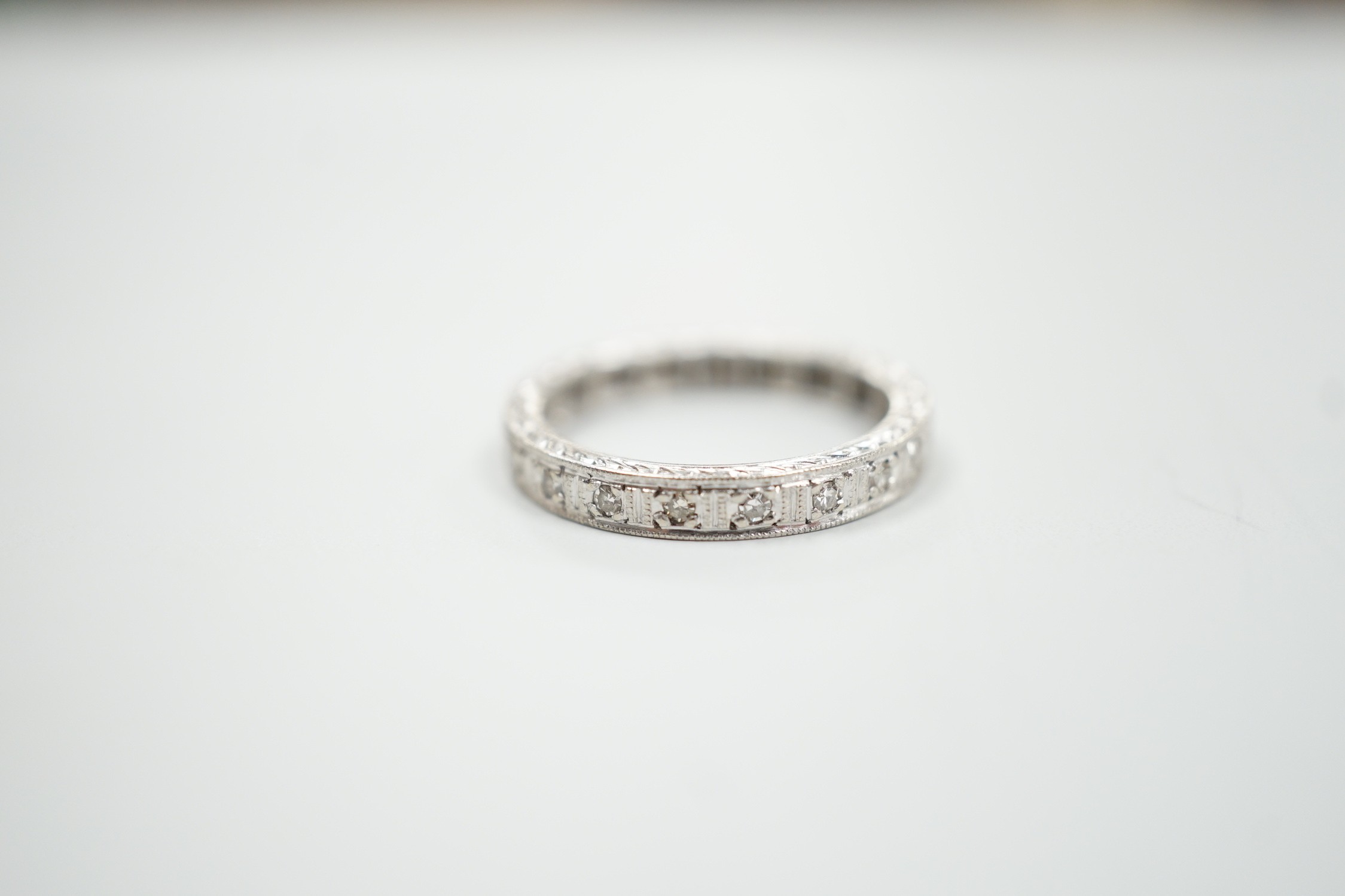 A white metal, stamped plat and diamond chip set full eternity ring, size K, gross weight 3.7 grams.